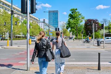Young women cross the road at pedestrian crossing, in modern European city