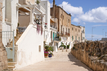 one of the beautiful narrow street decorated with flowers in the old town of Monopoli in the Puglia region, Italy