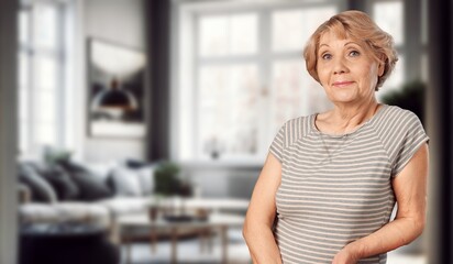 Fototapeta premium Portrait of pensive smiling older lady dreaming at home