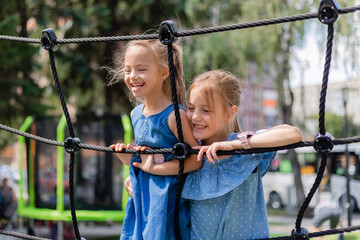 two happy little girls are playing in a children's town in the summer. A child with down syndrome