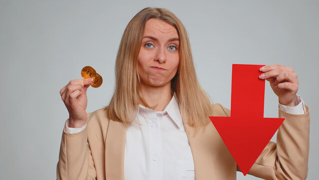 Business woman showing golden bitcoins indicating red arrow banner down sign decrease of exchange rate. Unsuccessful bankruptcy fall of stock cryptocurrency market investment mining BTC technology
