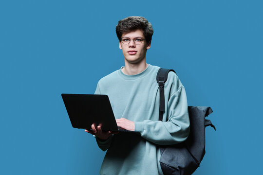 Young Male College Student Using Laptop, Blue Studio Background