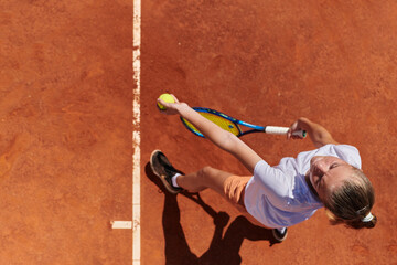 Top view of a professional female tennis player serves the tennis ball on the court with precision...