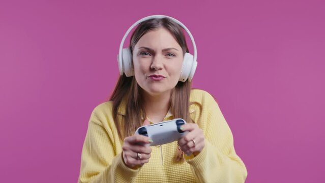 Young teenager girl playing online video game, console TV with joystick on pink