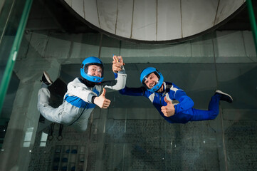 A man and a woman enjoy a joint flight in a wind tunnel and give a thumbs up. Free fall simulator.