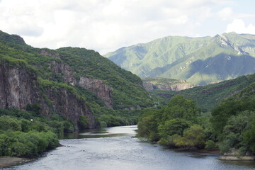 Fototapeta na wymiar Río en medio de montañas en la presa del Novillo, Sonora, México una tarde nubosa.