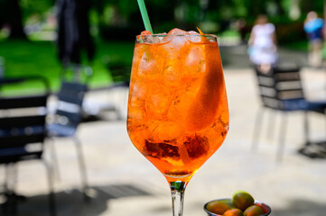 Waiter prepared the Aperol Sprits summer cocktail with Aperol, prosecco, ice cubes and orange in...