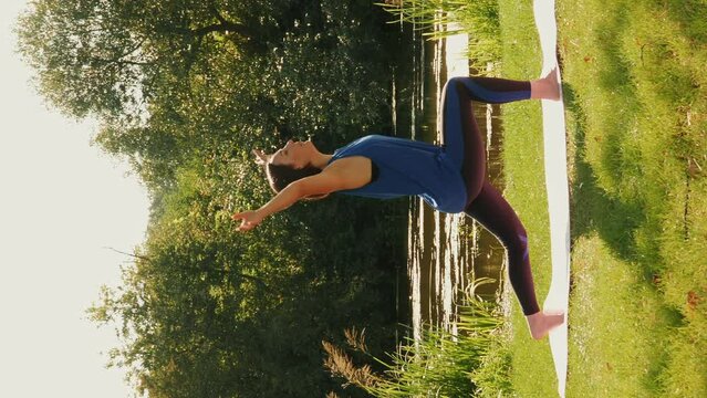 Outdoor yoga activity. Woman doing stretching exercises in park. Vertical video