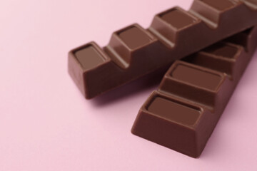 Delicious chocolate bars on pink background, closeup