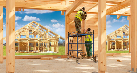 Construction of wooden house. Workers at construction site. Future cottage village. Two builders...