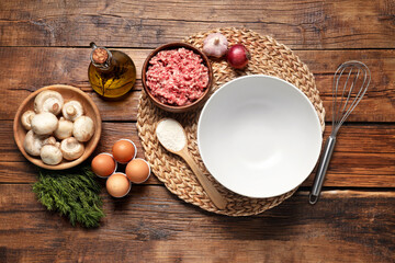 Bowl and different products on wooden table, flat lay