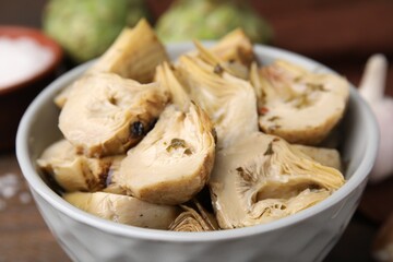 Bowl of pickled artichokes on table, closeup