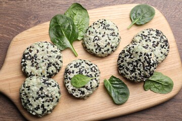 Tasty vegan cutlets with sesame seeds and spinach on wooden table, top view