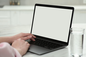 Fototapeta premium Woman using laptop at white table indoors, closeup