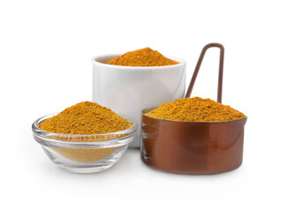Glass, bowl and scoop with curry powder on white background