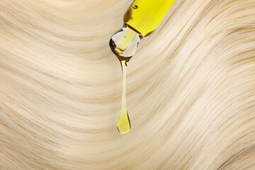 Obraz premium Dripping cosmetic oil from pipette onto blonde hair, closeup