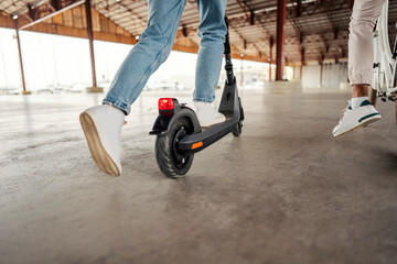 Obraz premium Cropped picture of legs on an electric scooter and on a bicycle in a capital city.