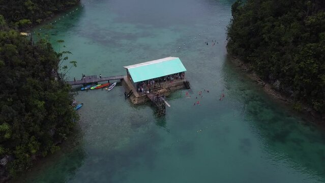 Aerial, Sugba Lagoon in Siargao island, Philippines.
Tourists swimming and jumping off a diving board at floating pontoon-style lodge.
