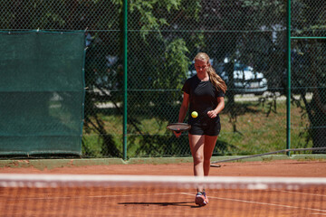 A young girl showing professional tennis skills in a competitive match on a sunny day, surrounded by the modern aesthetics of a tennis court.