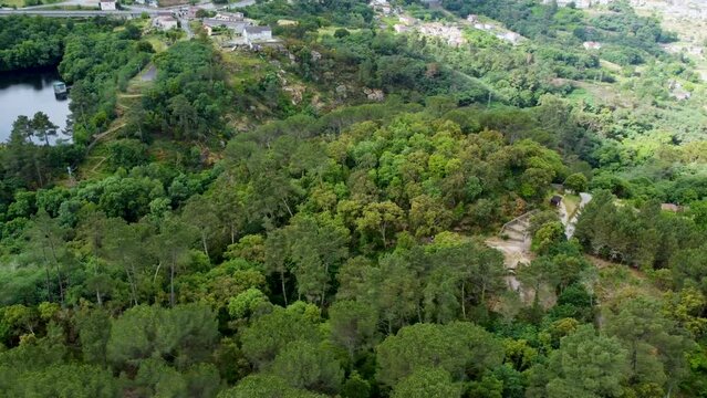 Aerial orbit above forested hillside reveals Castro de Santome ruins