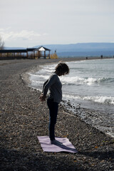 Elderly woman practices yoga alone, in front of Lake Buenos Aires, in Los Antigos, Argentine...