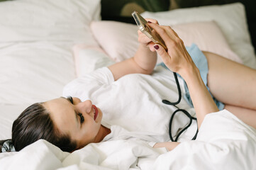 Positive young woman using smartphone on bed