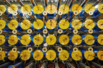 Bright yellow spools on shiny metal rods in plant workshop