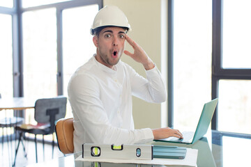 young handsome man looking happy, astonished and surprised. architect concept