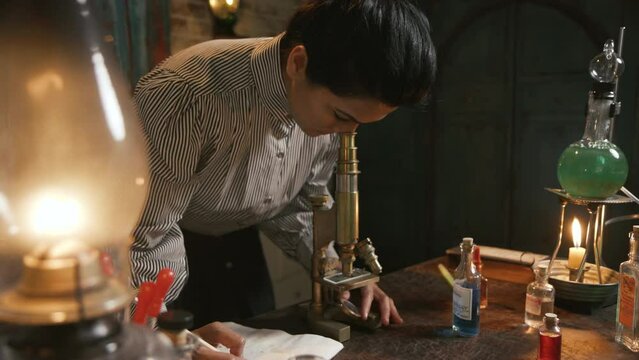 victorian scientist looks through microscope and takes notes