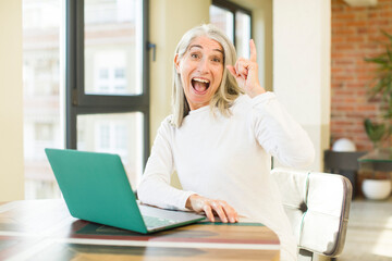 senior pretty woman feeling like a happy and excited genius after realizing an idea with a laptop
