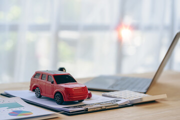 Toy car and laptop calculator on desk. Buy, sell, rent, repair or insurance, small business, car...
