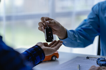 Young salesman holding car keys in hands of car rental business customer sell or buy services Asian...
