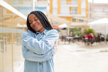 Fototapeta premium afro pretty black woman feeling in love, smiling, cuddling and hugging self, staying single, being selfish and egocentric