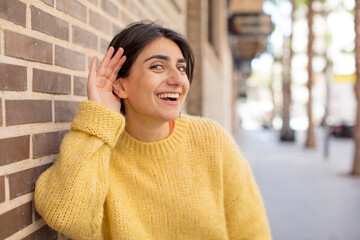 pretty woman looking happy, listening, trying to hear a secret conversation or gossip, eavesdropping