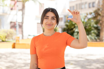 pretty woman holding an object ,showing, offering or advertising something small