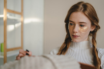 Satisfied woman sitting on sofa in the living room and writing in a journal her plans and goal. Woman thinking. Diary plan.