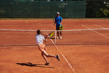 A professional tennis player and her coach training on a sunny day at the tennis court. Training and preparation of a professional tennis player