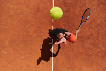 Top view of a professional tennis player serves the tennis ball on the court with precision and power