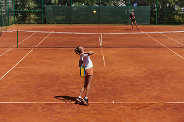 Young girls in a lively tennis match on a sunny day, demonstrating their skills and enthusiasm on a modern tennis court.