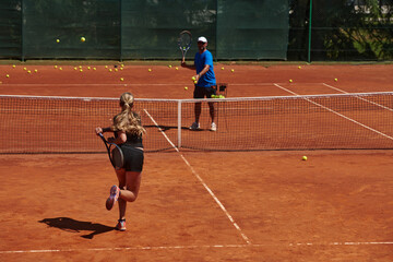 Fototapeta premium A professional tennis player and her coach training on a sunny day at the tennis court. Training and preparation of a professional tennis player