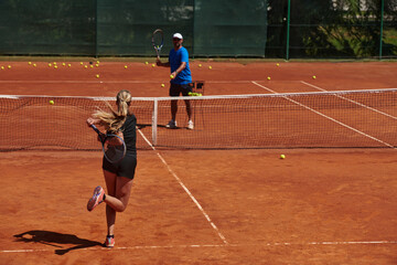 Fototapeta premium A professional tennis player and her coach training on a sunny day at the tennis court. Training and preparation of a professional tennis player