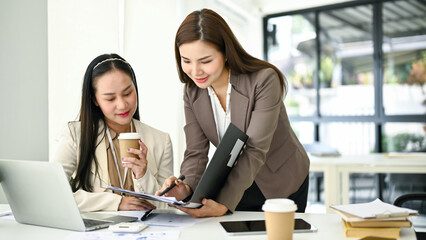 A female boss is briefing and explaining a new project to her employee in the office.