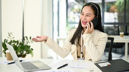 A businesswoman dealing business over the phone with her client at her desk