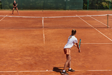 Young girls in a lively tennis match on a sunny day, demonstrating their skills and enthusiasm on a modern tennis court.