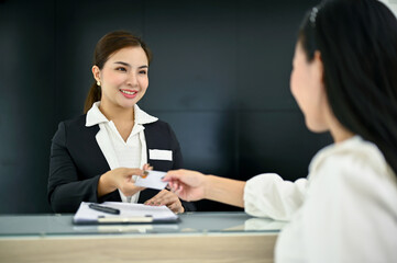Friendly Asian female receptionist greeting and welcoming a customer with beautiful smile