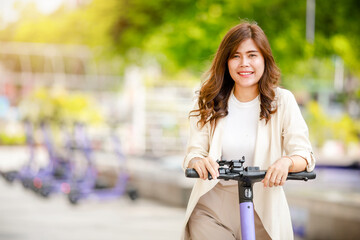 Fashionable lady in suit rides electric scooterto work along office buildings.