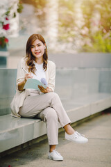 Stylish business woman holding documents in hand  walking around town near office towers, working outside.
