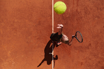 Top view of a professional female tennis player serves the tennis ball on the court with precision...