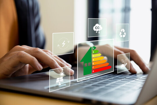 Home improvement concept, Hand of businessman using laptop with energy efficiency rating, ecological and bioenergetic house, efficiency scale.