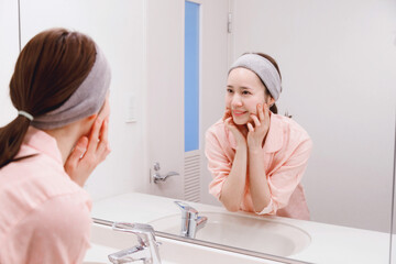 日本人女性が顔にローションを塗っています